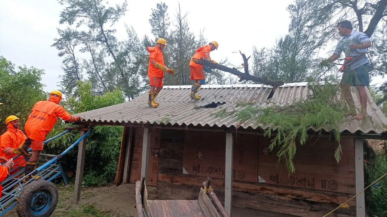 NDRF personnel remove an uprooted tree from the roof of a house after the landfall of Cyclone 'Remal', in South 24 Parganas district, Monday, May 27, 2024
