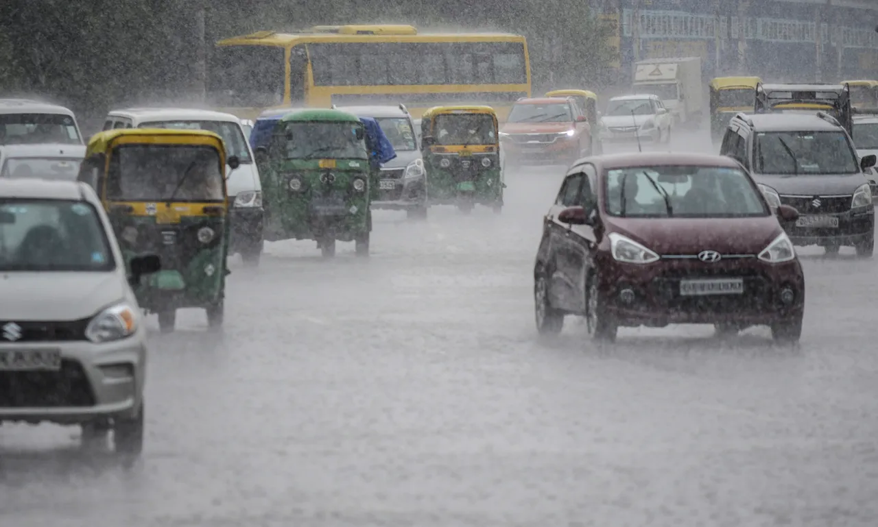 Vehicles ply on a road amid rainfall, in Gurugram