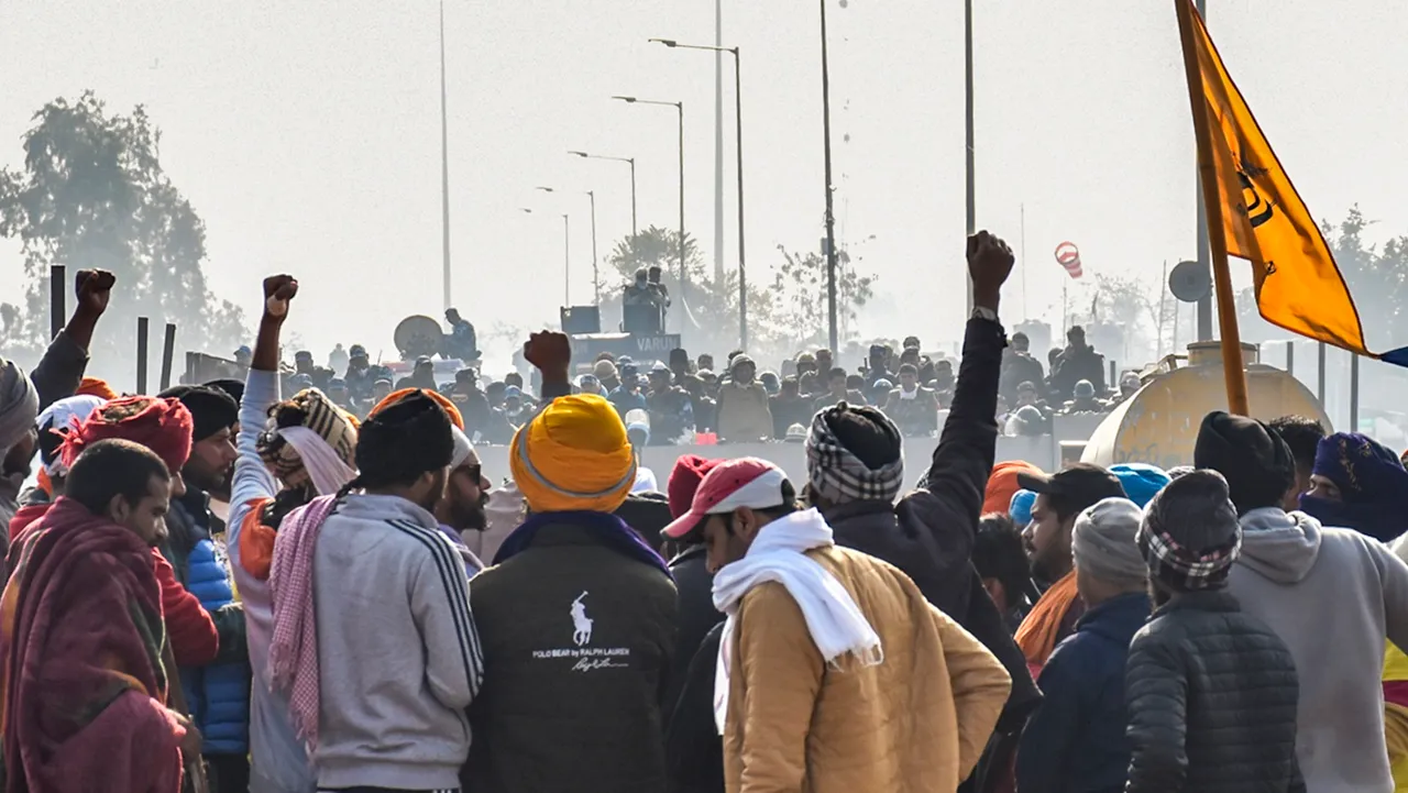 Farmers raise slogans in front of security personnel guarding at the Punjab-Haryana Shambhu border during their 'Delhi Chalo' protest