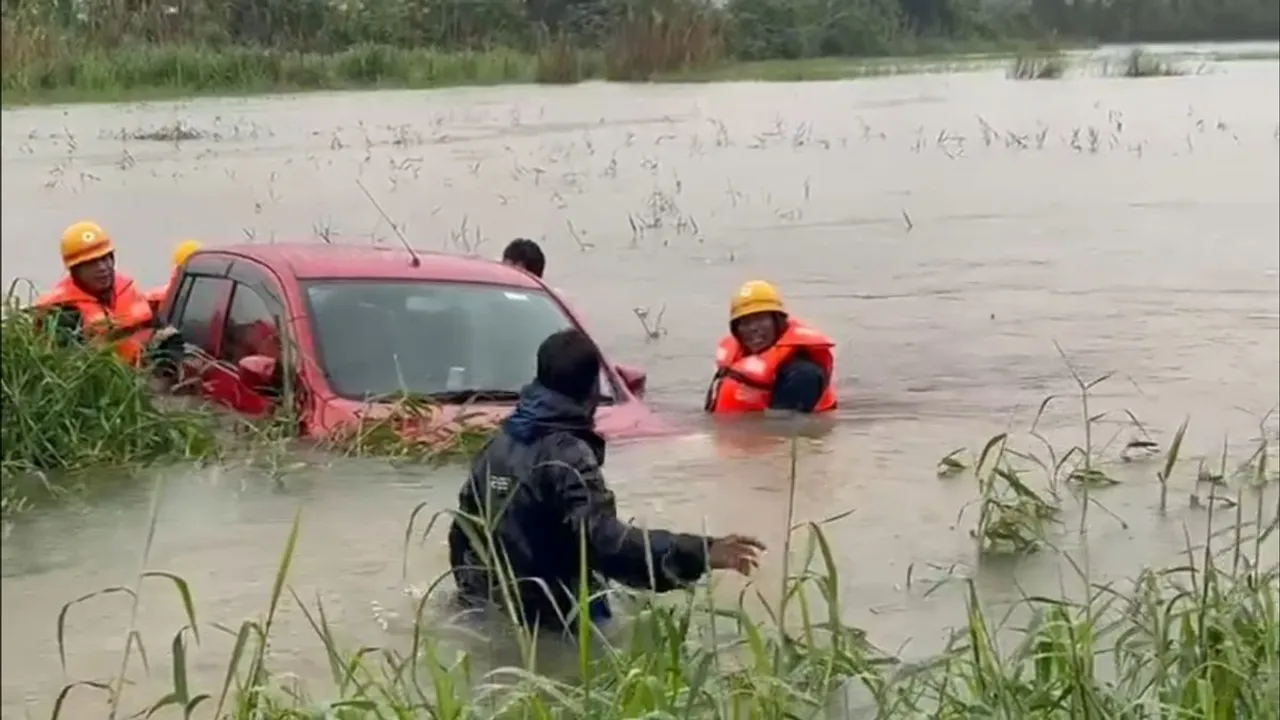 Rescue teams and locals pull car from flooded paddy fields in Udupi, Karnataka.
