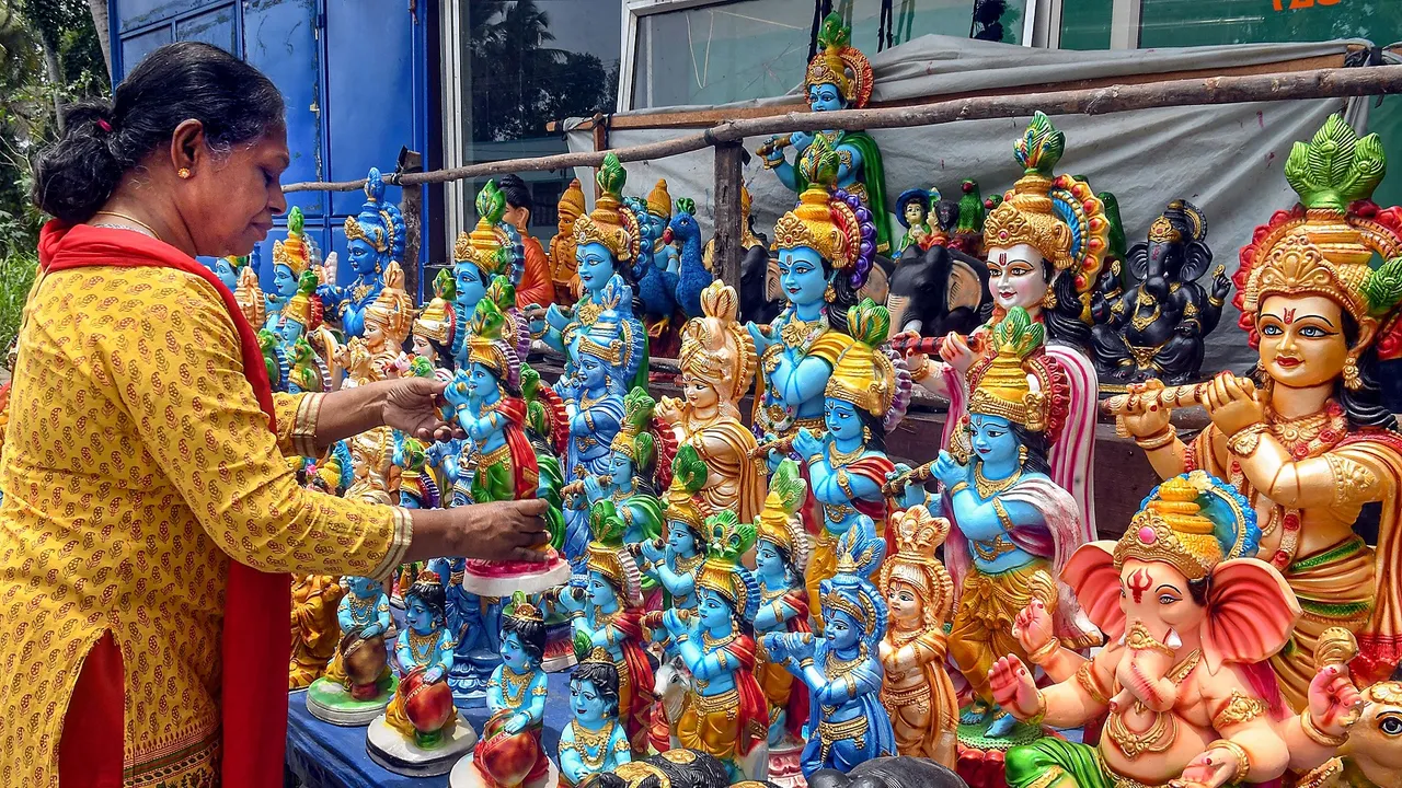 A devotee selects an idol of Lord Krishna to purchase ahead of the Janmashtami festival, in Thiruvananthapuram