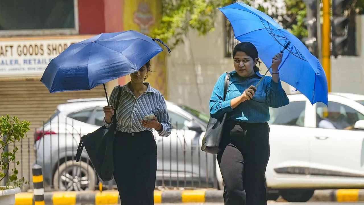 Women cover themselves under umbrellas during heatwave, in New Delhi, Saturday, June 14, 2024