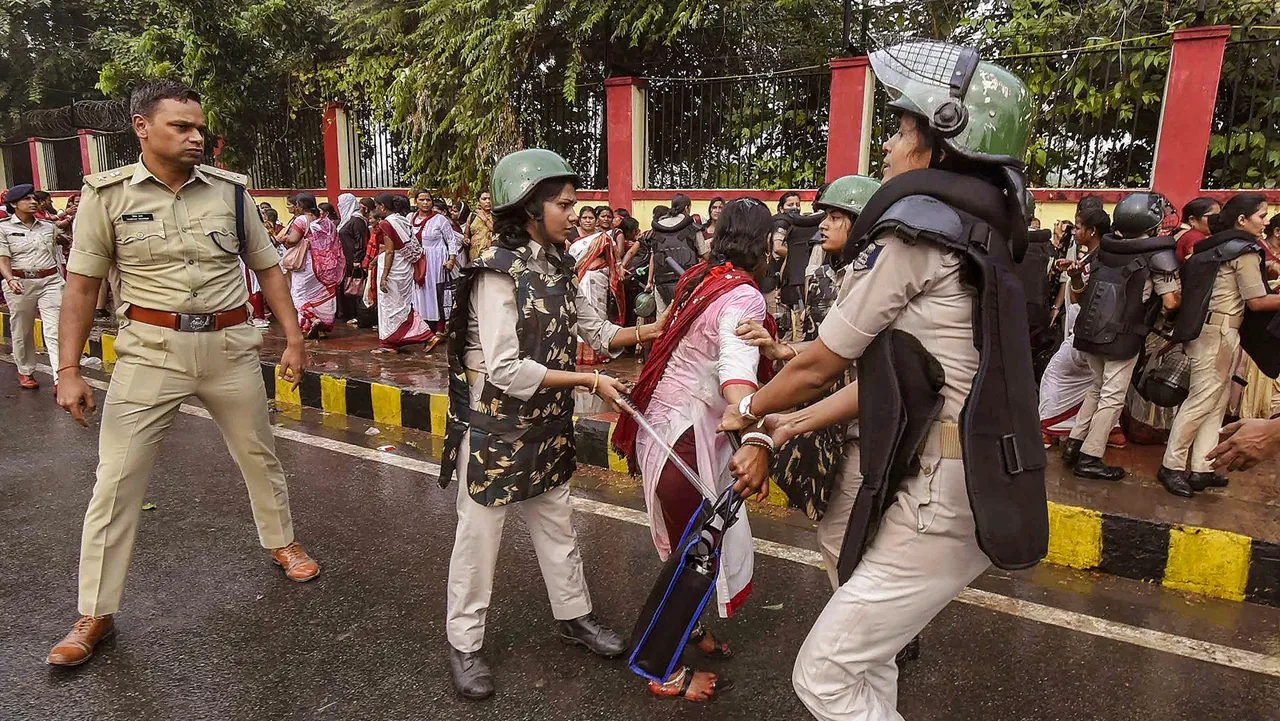 Security personnel detain Anganwadi workers protesting outside the Bihar Legislative Assembly, in Patna