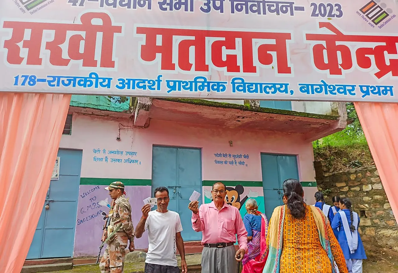 Voters show their identification cards as they arrive to cast their votes during the by-elections to Bageshwar assembly seat, in Uttarakhand's Bageshwar district