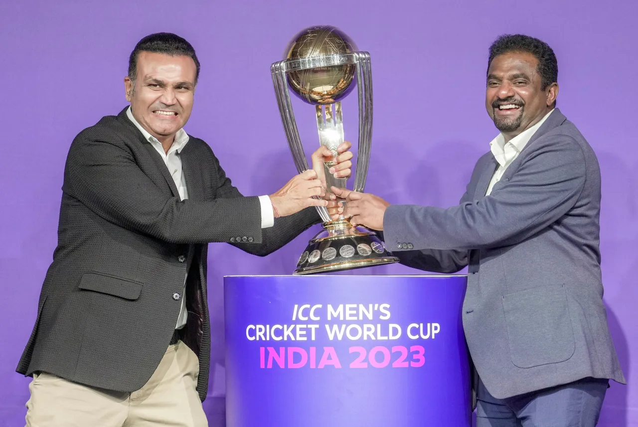 Former Indian cricketer Virender Sehwag and former Sri Lanka cricketer Muttiah Muralitharan pose with ICC Men's Cricket World Cup trophy
