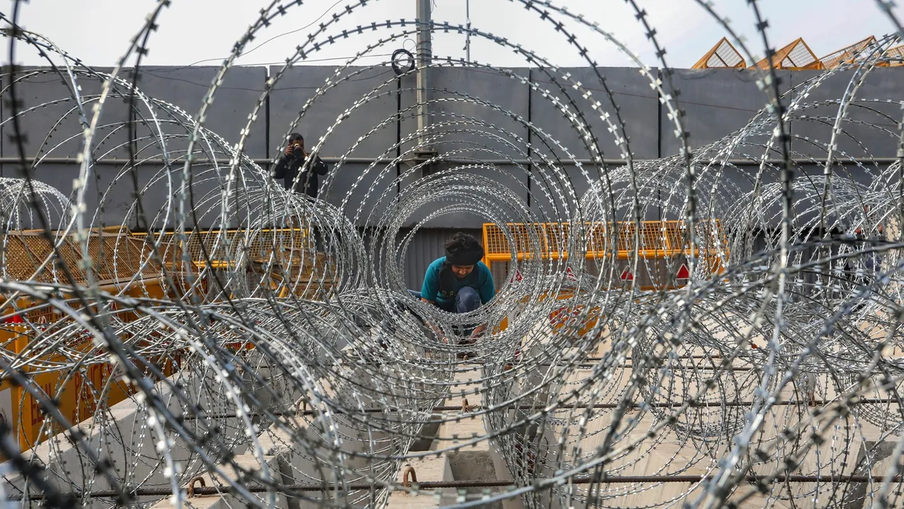 A worker lays down barbed wire on National Highway 44 in view of farmers' 'Delhi Chalo March', near Singhu border in Sonipat district