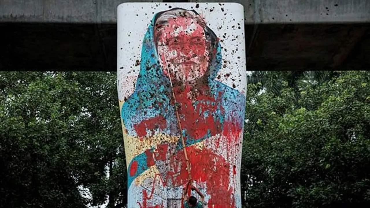 A protester vandalises a mural of Bangladeshi Prime Minister Sheikh Hasina with paint in Dhaka