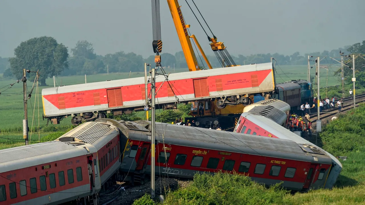 A crane removes a derailed coach of North East Express from the track a day after its derailment near Raghunathpur railway station in Buxar district