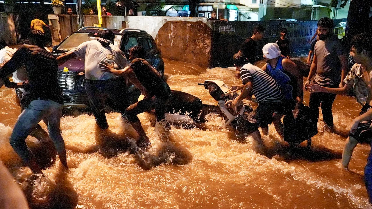 People try to pull a two-wheeler from being swept away by rainwater near Old Rajinder Nagar during the rain, in New Delhi, Wednesday, July 31, 2024.