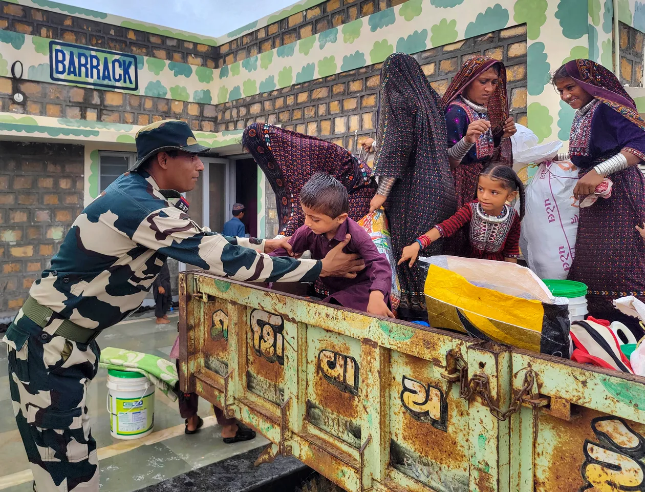 A BSF officer helps a child to get down from a tractor as evacuation process is underway ahead of the expected landfall of Cyclone Biparjoy, at Gunau village of kutch district