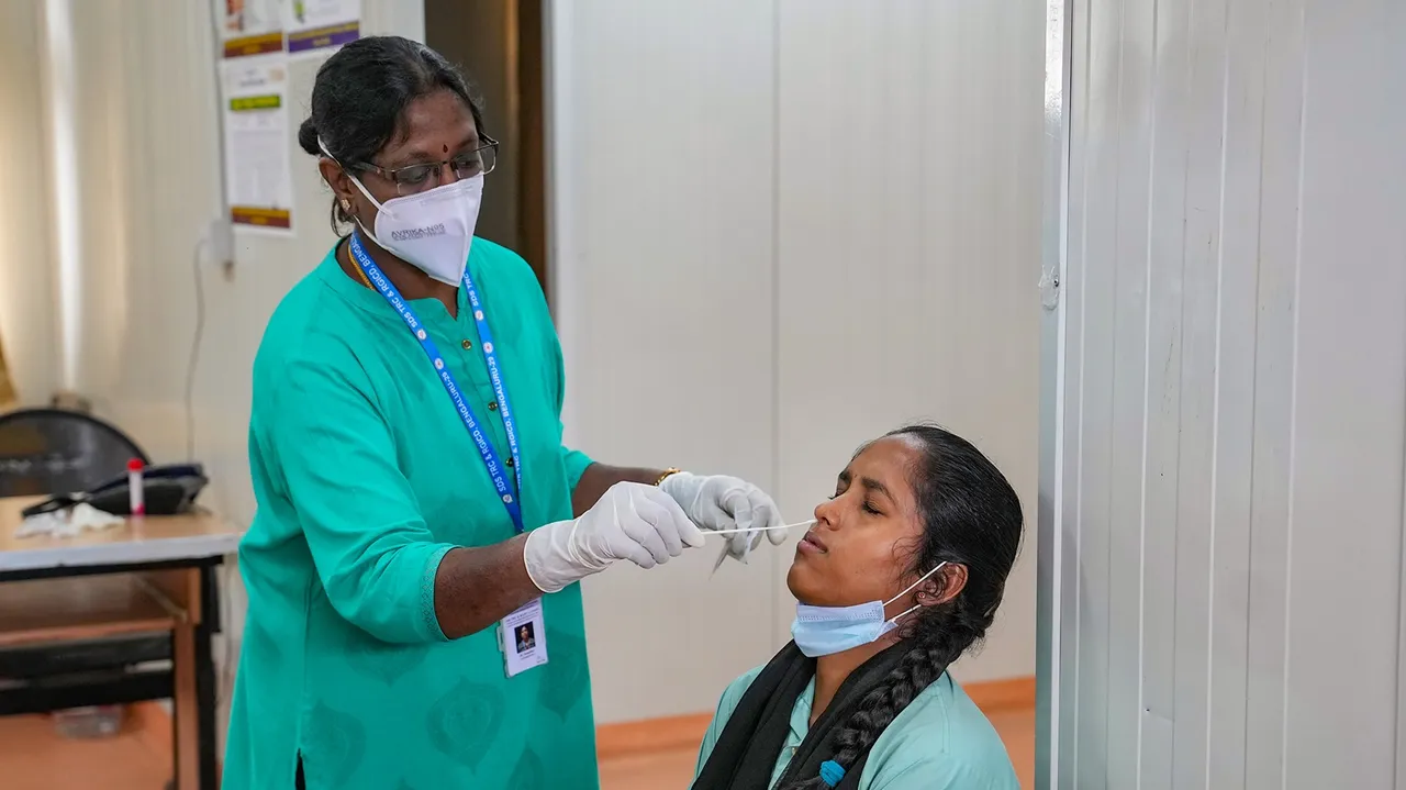 A medical staff conducts covid-19 test of a woman at Rajiv Gandhi institute of Chest Disease in Bengaluru