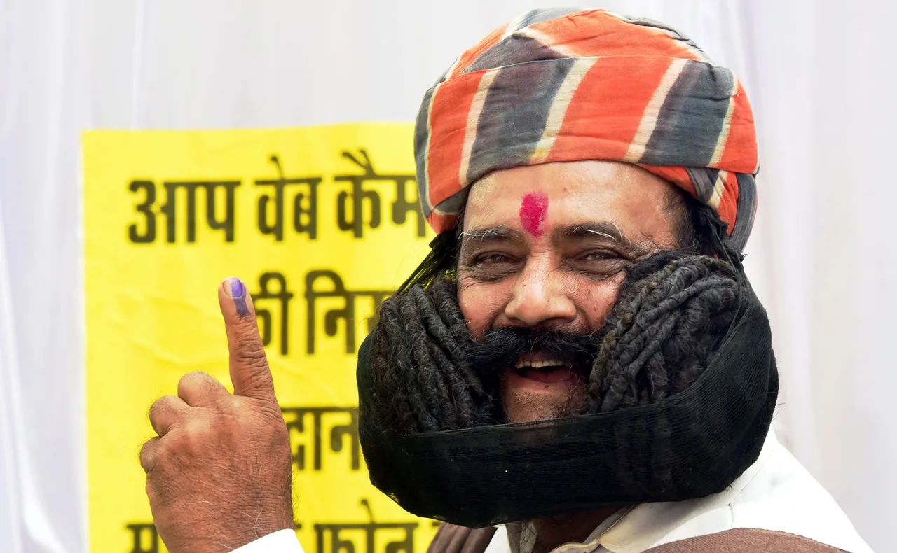 Girdhar Vyas, who claims to have the longest moustache in the world, shows his finger marked with indelible ink after casting his vote for the Rajasthan Assembly elections, in Bikaner