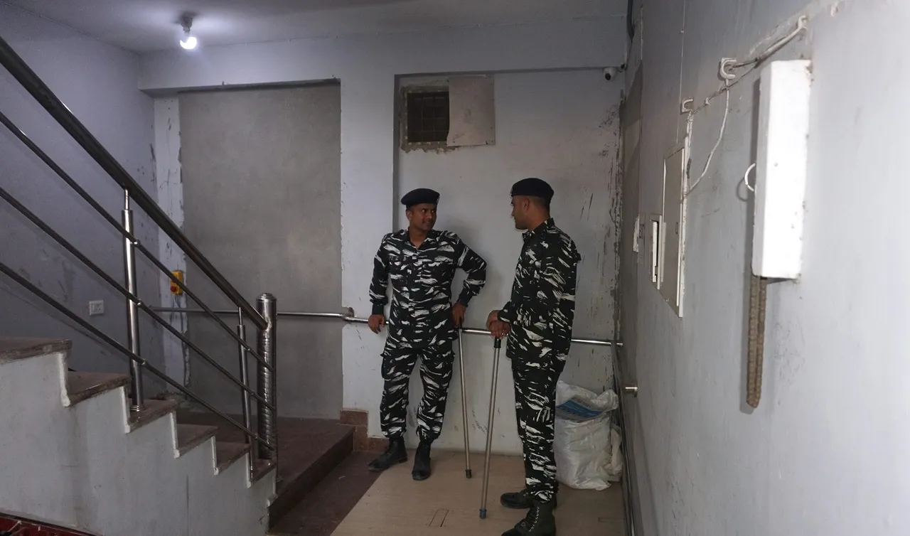 Security personnel guard during raids by Delhi Police's Special Cell on the premises of NewsClick at Sainik Farm, in New Delhi