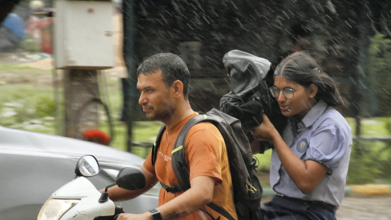 Commuters on a road amid rain in Gurugram