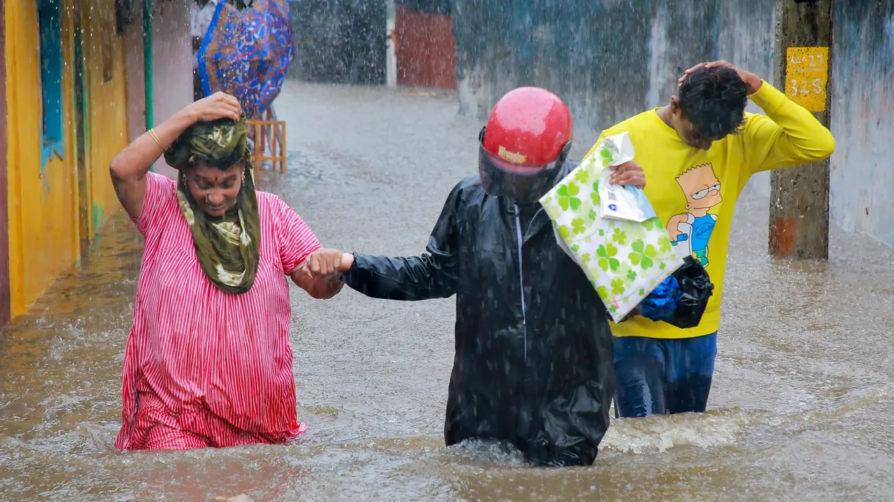 People make their way through a waterlogged street due to continuous heavy rain, in Kanyakumari district