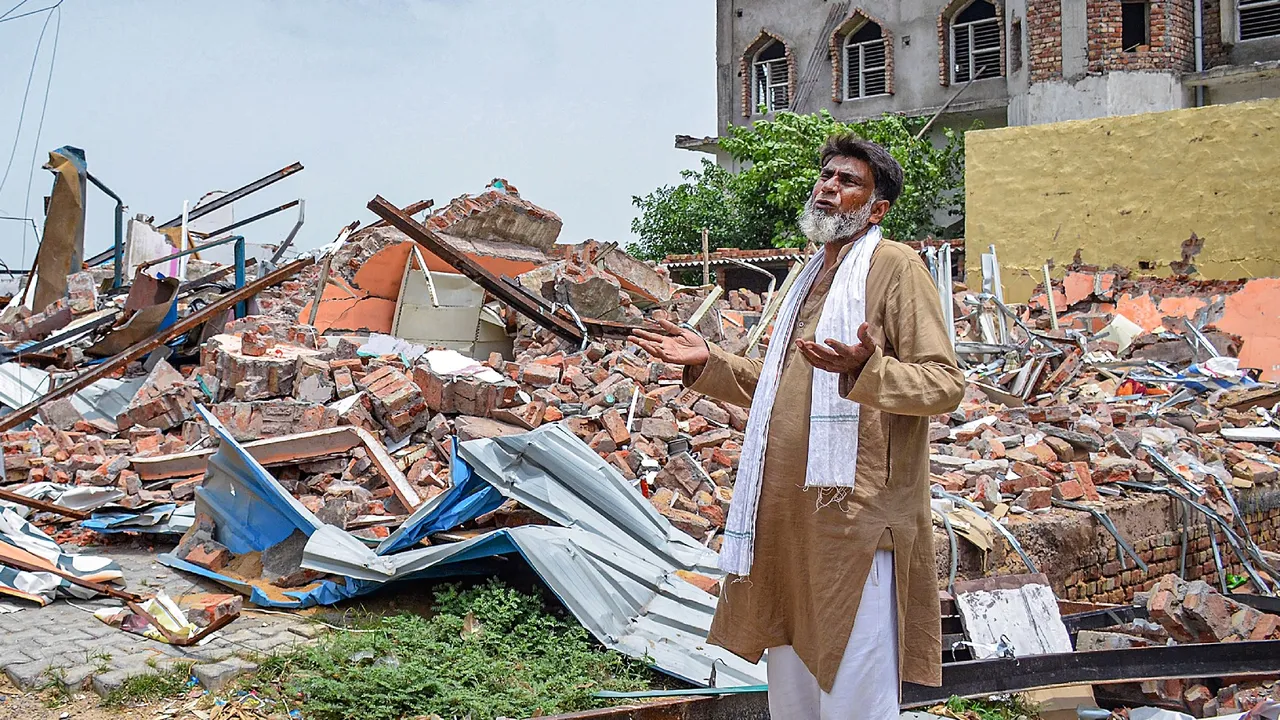 A shopkeeper stands near the debris of shops demolished by the administration in a drive against illegal construction, in Nuh district
