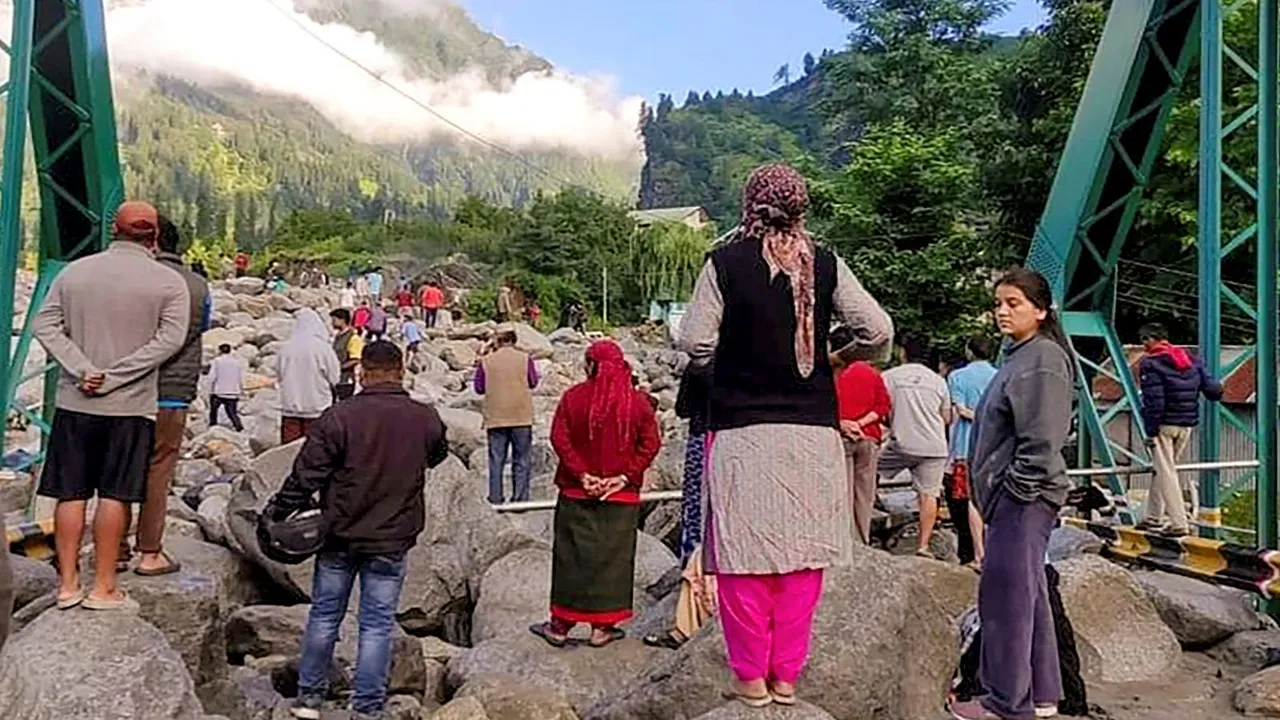 People stand near debris after flash floods triggered by cloud burst, near Manali, Thursday, July 25, 2024.