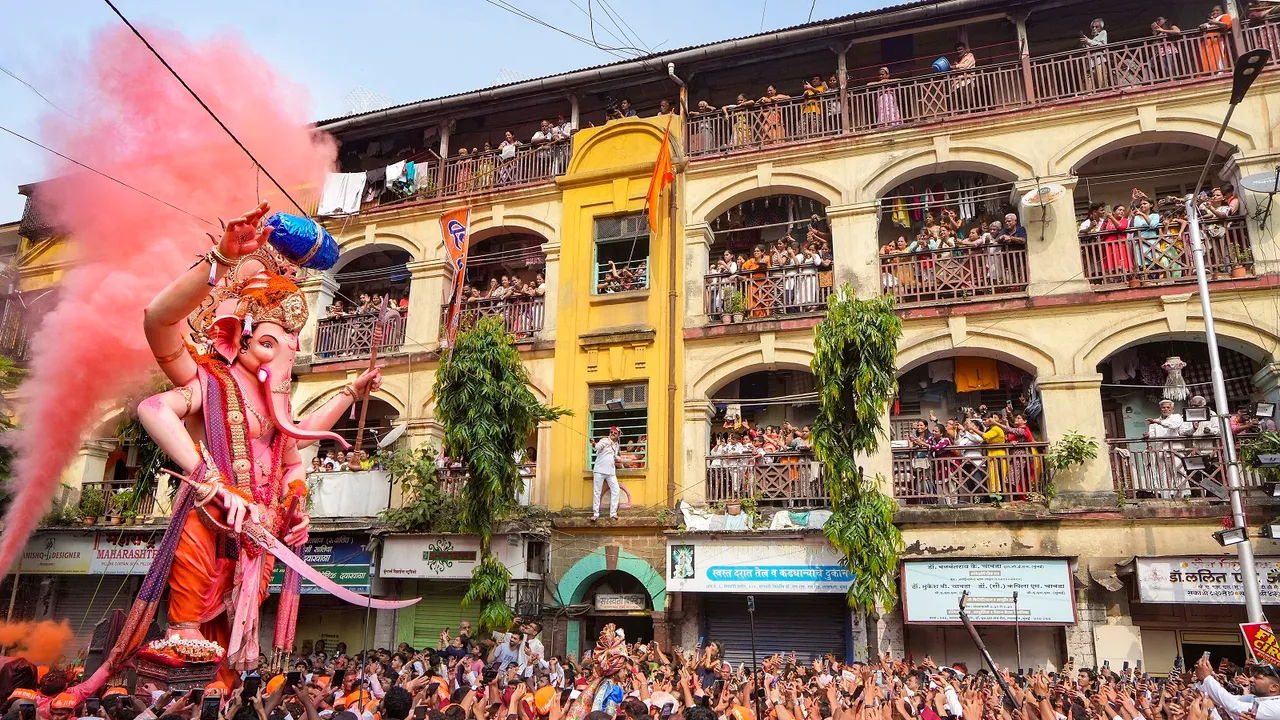 People watch devotees celebrate in a ‘Ganesh Visarjan’ procession for immersion of the idol of Lord Ganesha during 'Ganesh Chaturthi' festivities, in Mumbai