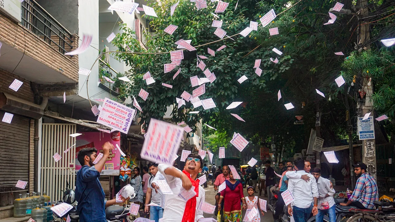 Students throw pamphlets at the College Of Vocational Studies during Delhi University Students' Union (DUSU) polls, in New Delhi, Friday