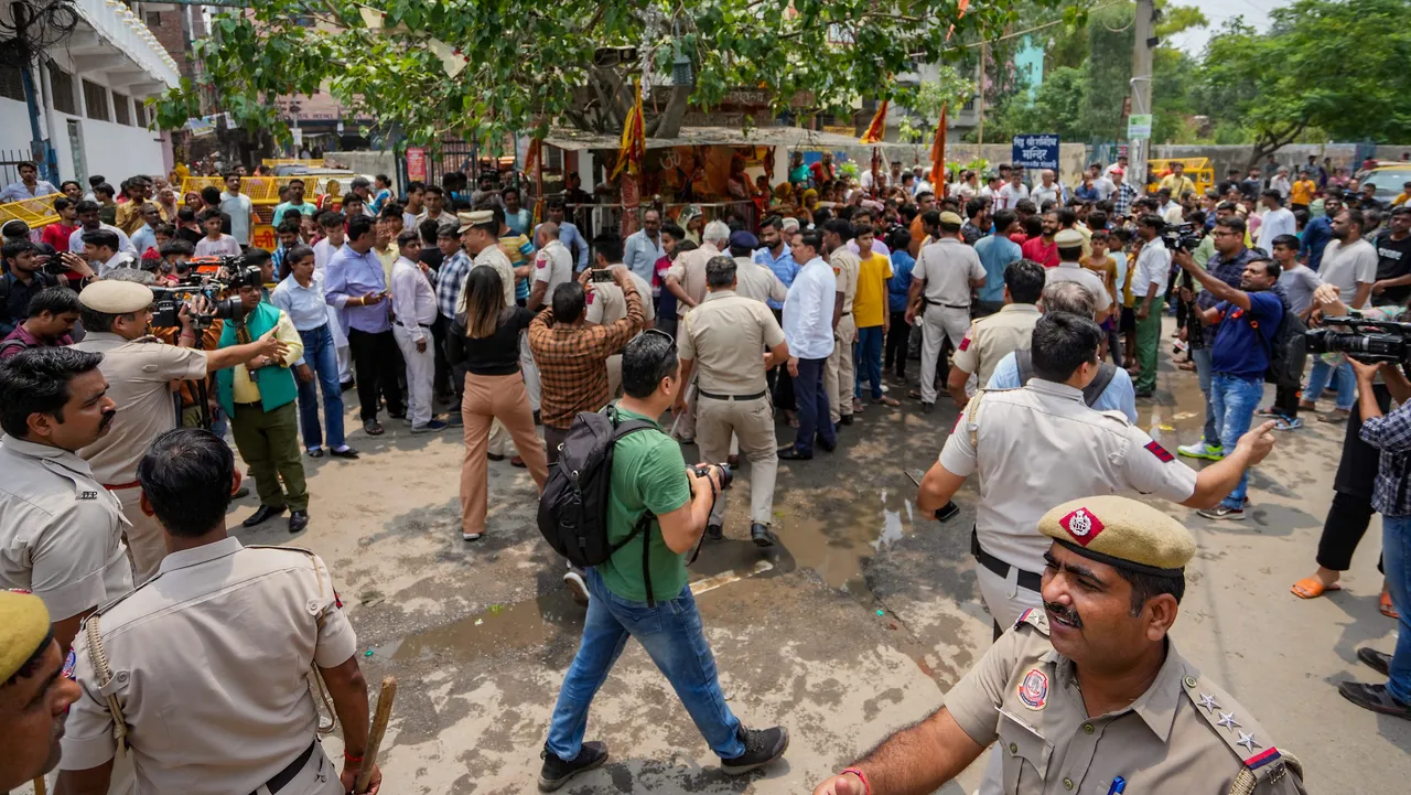 Police personnel attempt to pacify locals protesting against the removal of a portion of a temple in Mandawali area of New Delhi