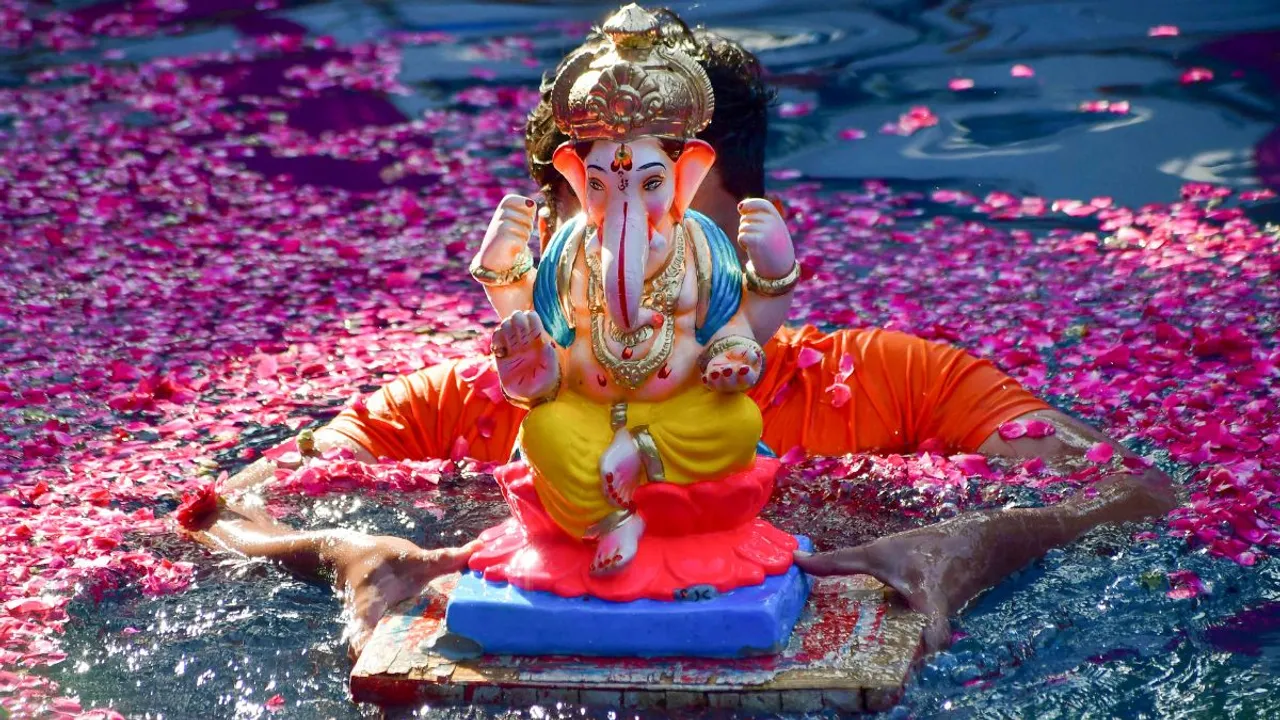 A volunteer immerses a Lord Ganesha idol in an artificial pond during Ganesh Utsav, at Dadar, in Mumbai, Sunday, Sept. 8, 2024