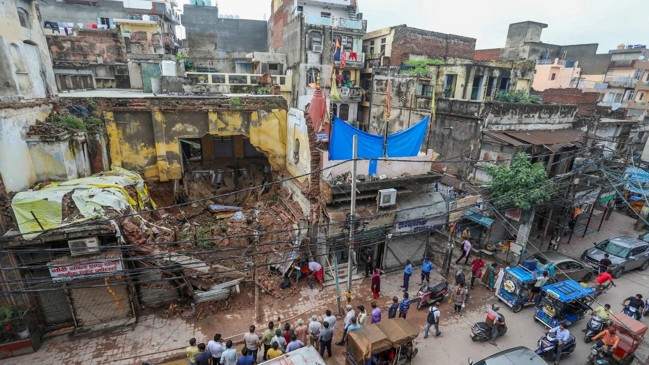 Local shop owners and residents near the debris of the house that collapsed due to heavy rains in Sabzi Mandi area, in New Delhi, Thursday, Aug. 1, 2024.