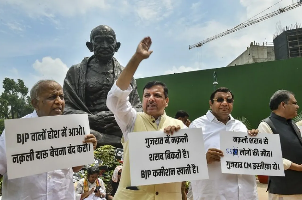 AAP MPs stage a protest over Gujarat hooch tragedy near the Gandhi statue during the ongoing Monsoon Session of Parliament, in New Delhi, Wednesday