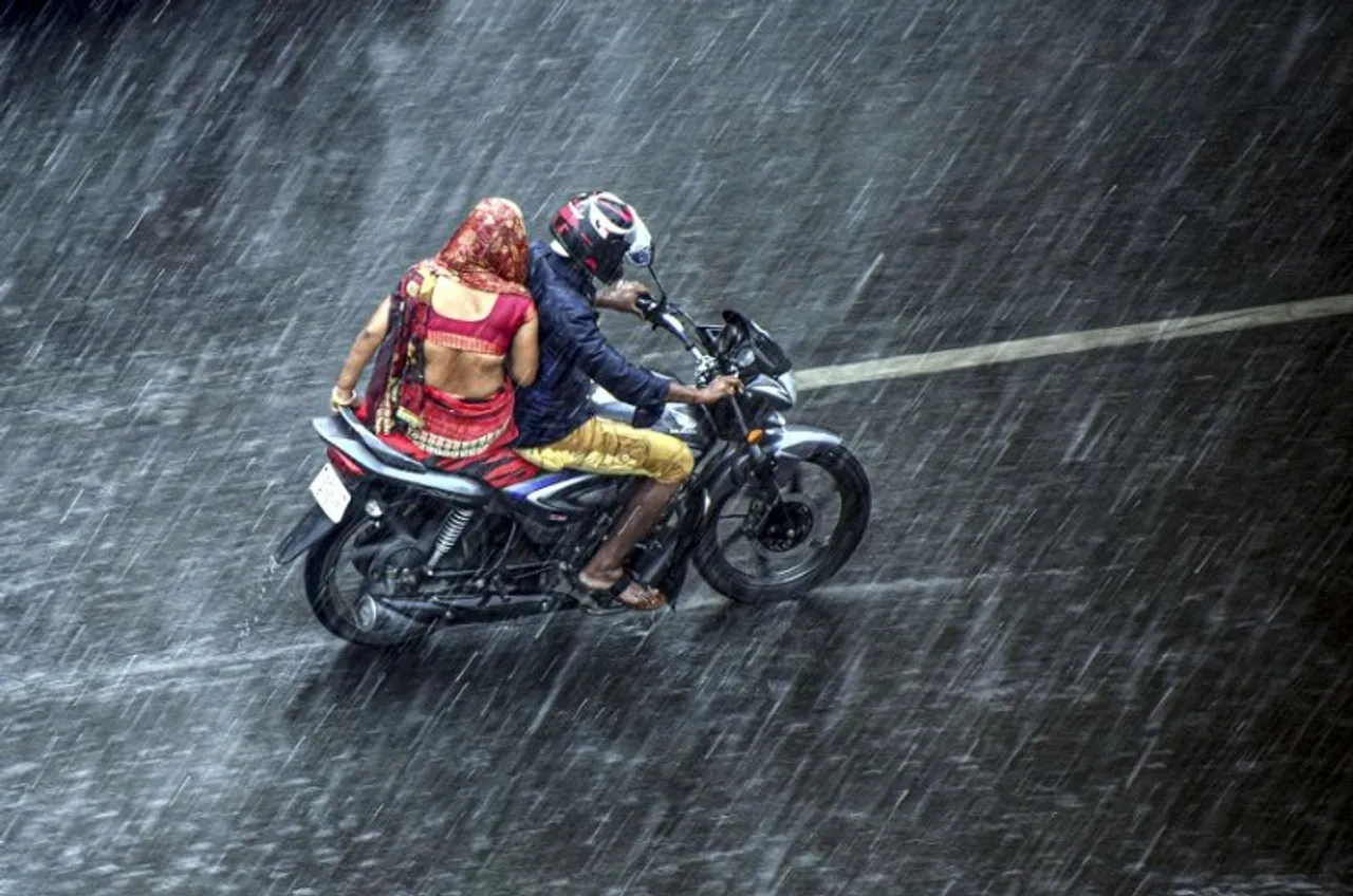 Commuters ride a bike during rain
