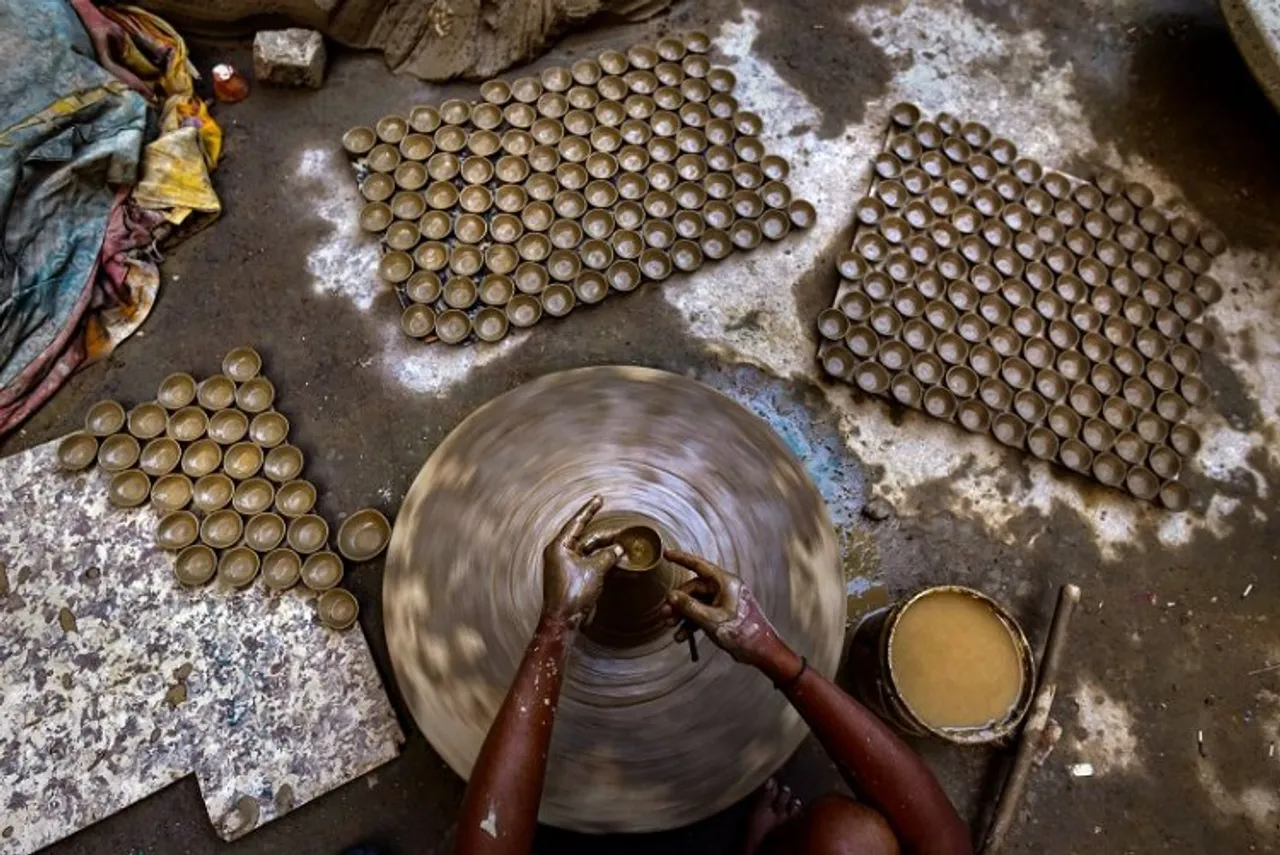 A potter moulds an earthen lamp (diya) on a wheel, ahead of the Diwali festival