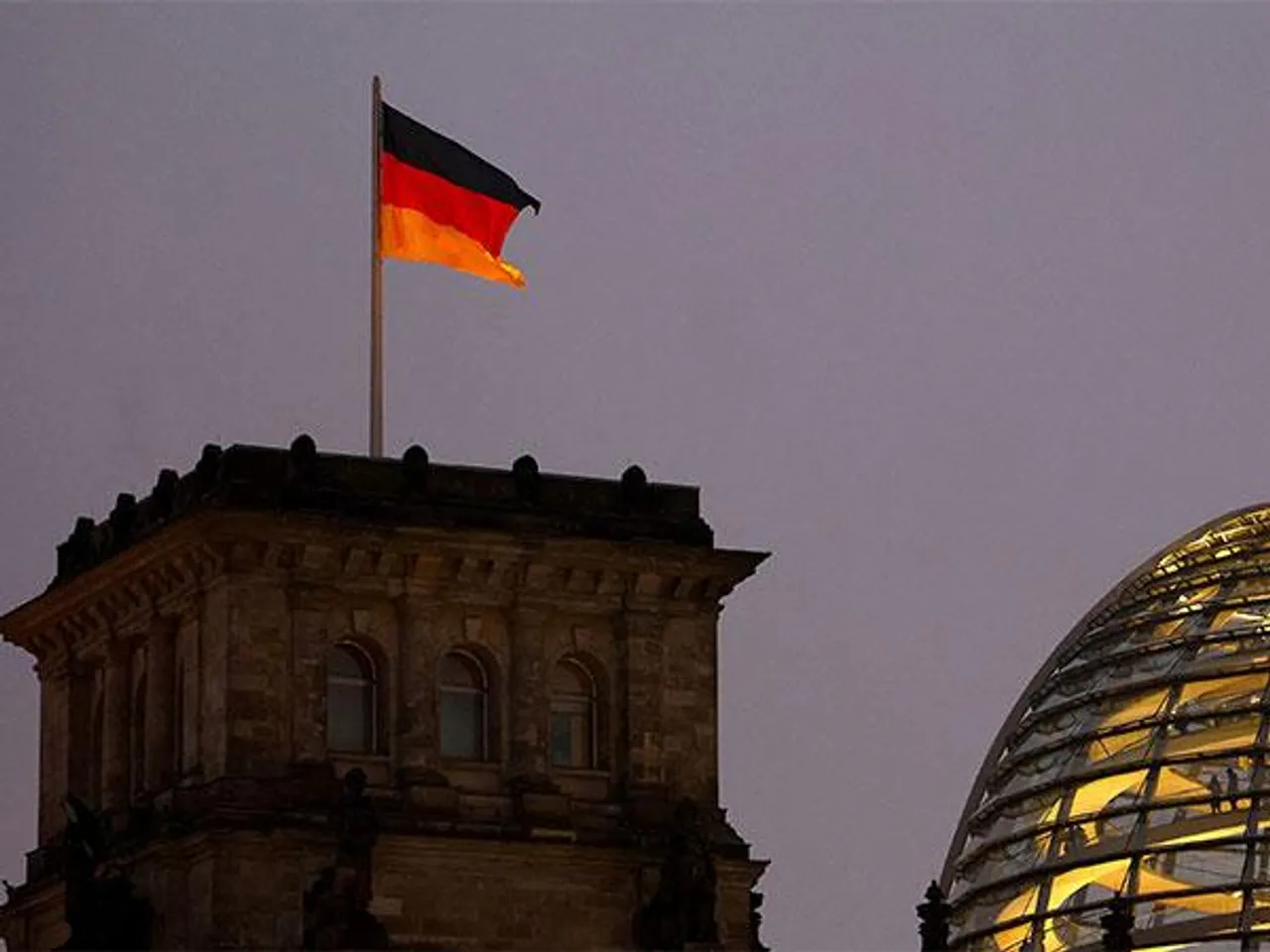 German national flag flying atop the illuminated Reichstag building, the seat of the Bundestag, Germany’s lower house of parliament, in Berlin (Source: Reuters)