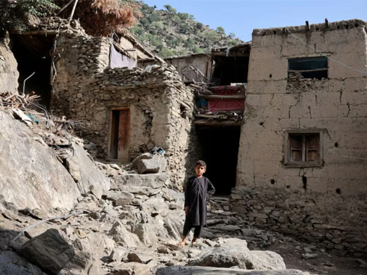 A boy stands in front of houses damaged by a deadly earthquake that struck Afghanistan's Kunar and Nangarhar provinces, at Masud village in Nurgal district, Kunar province, Afghanistan (Image/Reuters)