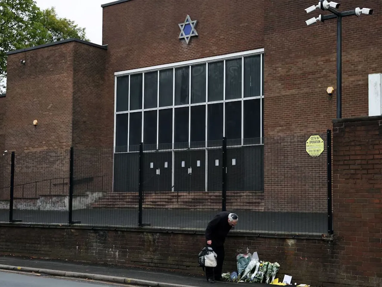 A man looks at floral tributes outside the Manchester synagogue, where multiple people were killed on Yom Kippur (Photo/Reuters)