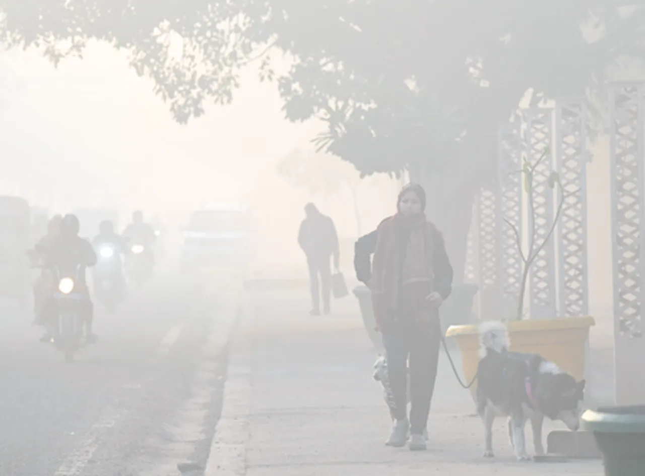 Noida: Commuters walk along a road amid smog on a chilly morning