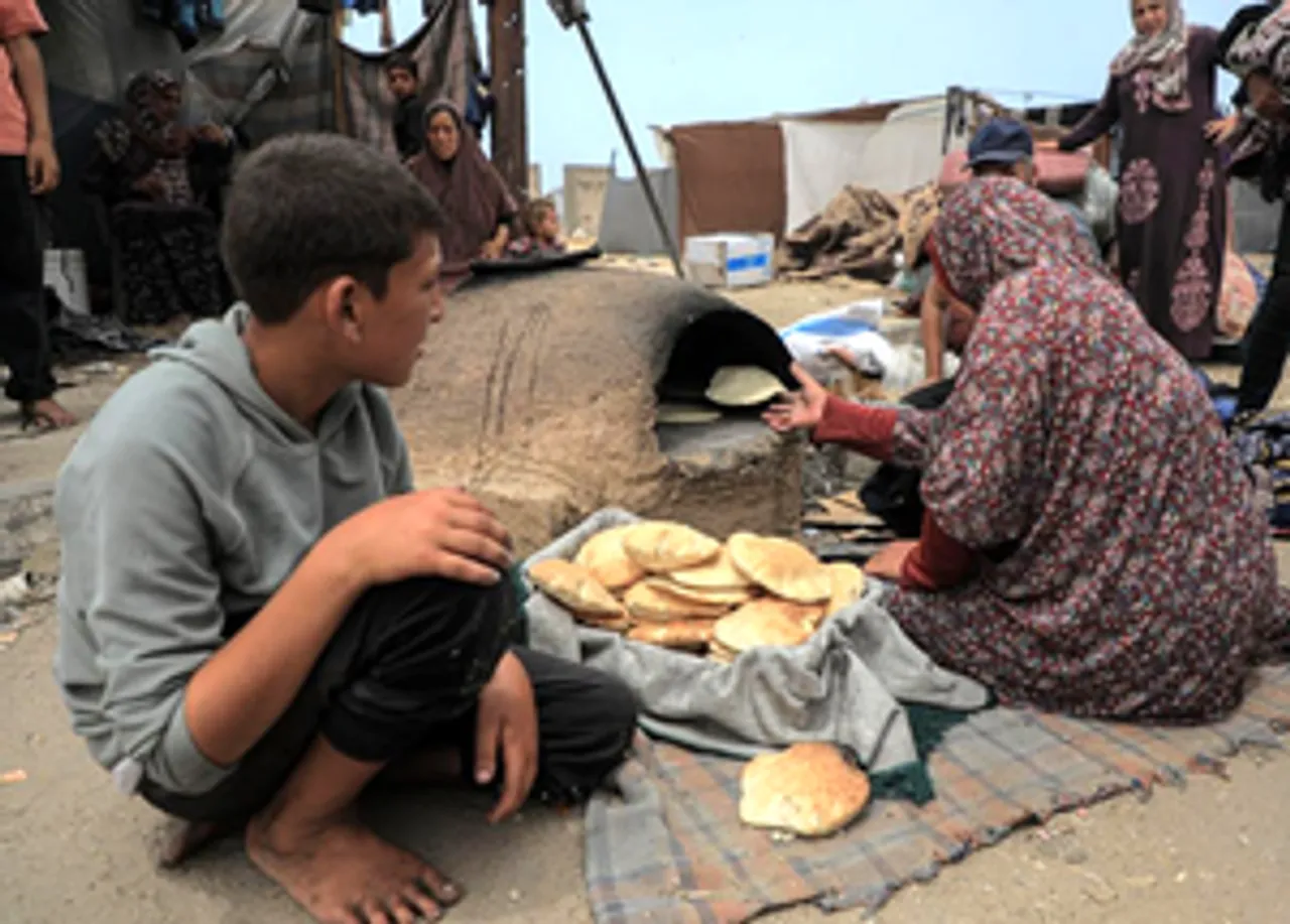 A Palestinian woman makes bread at a temporary camp in the southern Gaza Strip city of Rafah