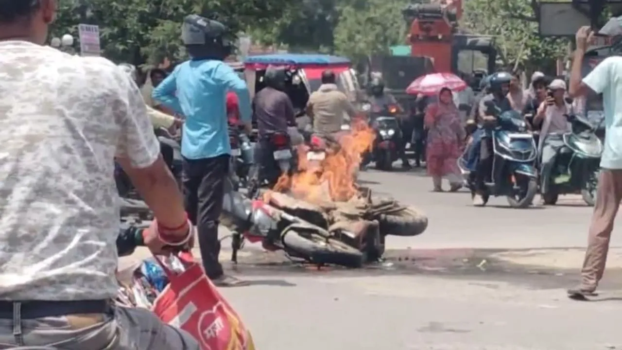 धू-धू कर जलती बाइक और आसपास खड़े लोग।