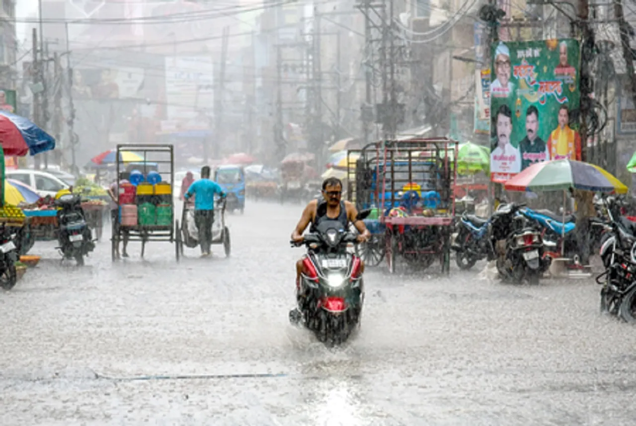 Commuters wade through heavy rainfall in Patna on Friday