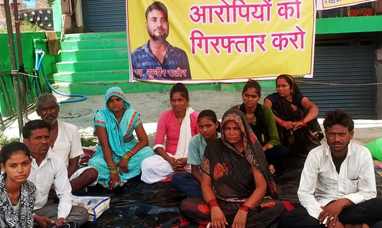 अल्हागंज में हाईवे किनारे धरने पर बैठे सुधीर राठौर के परिजन।