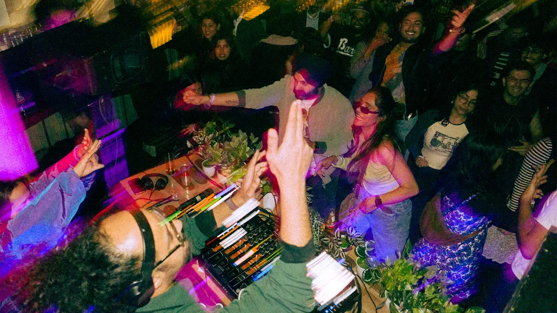  A DJ dances as he spins the records and plays to a crowd that's also dancing, showing how DJs in India are changing electronic music in India as well as an increase in the number of Indian DJs in music festivals in India as well as the advent of coffee raves India 