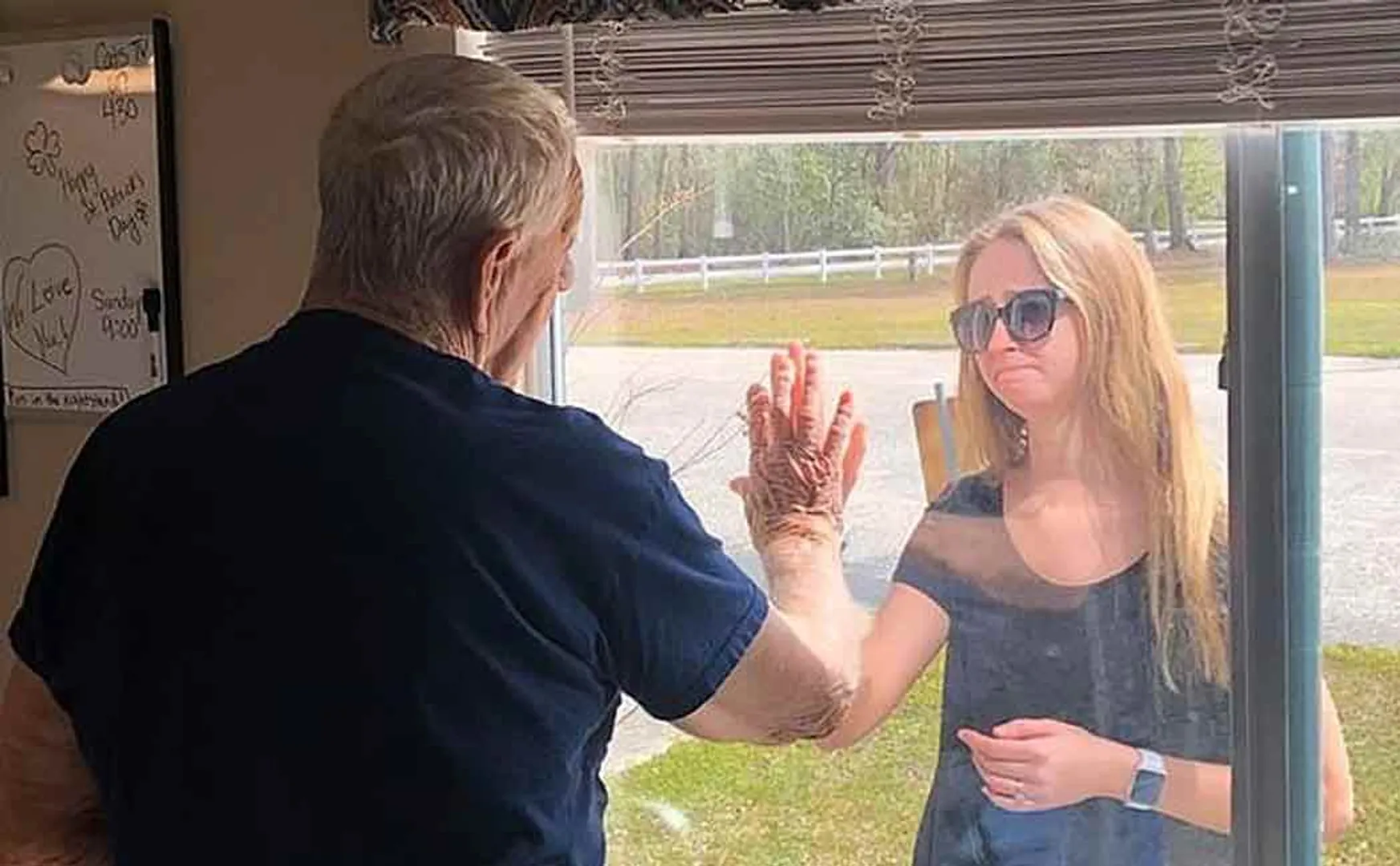 Woman shows engagement ring to her grandfather through window