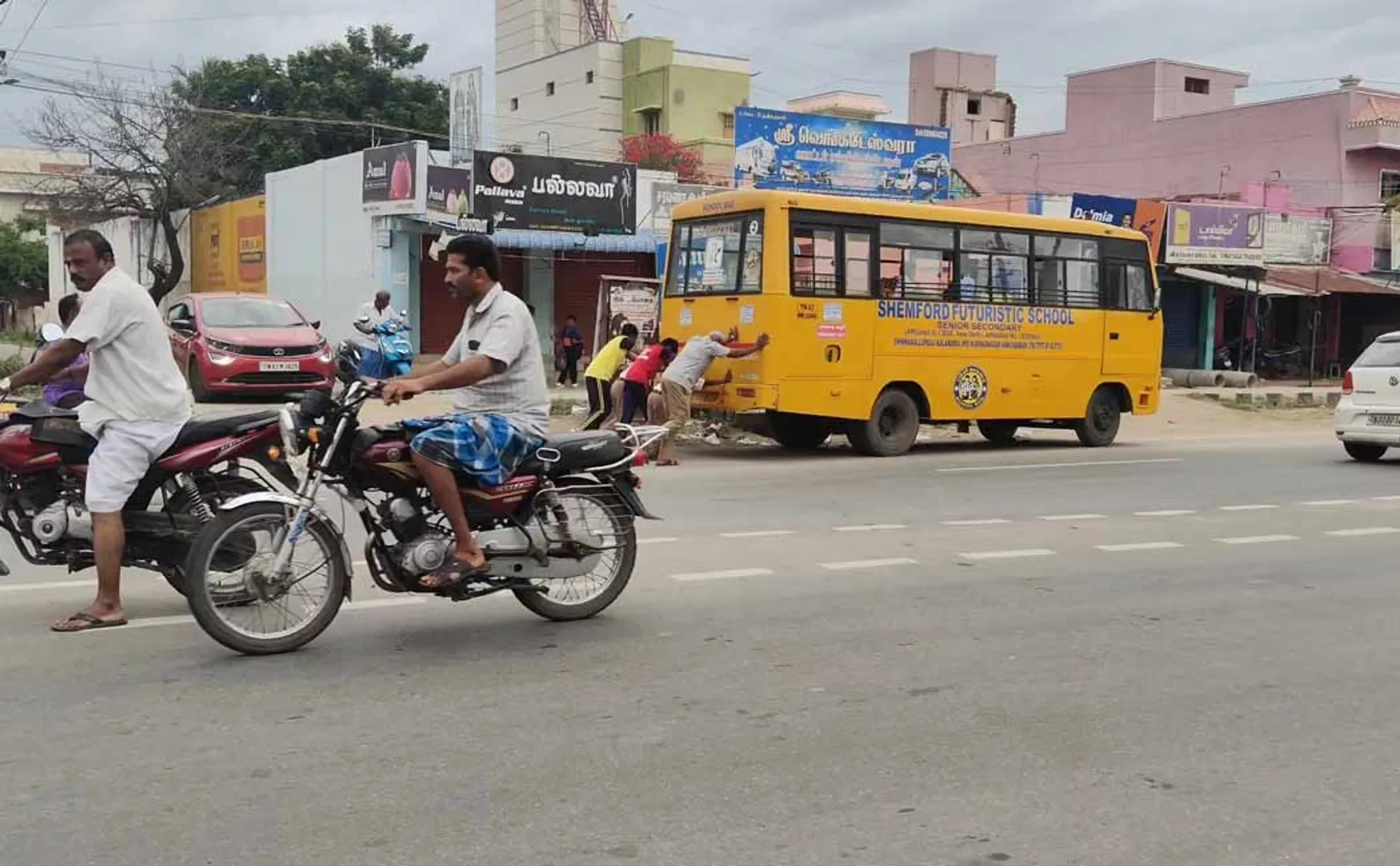 Students pushing a broken-down private school vehicle