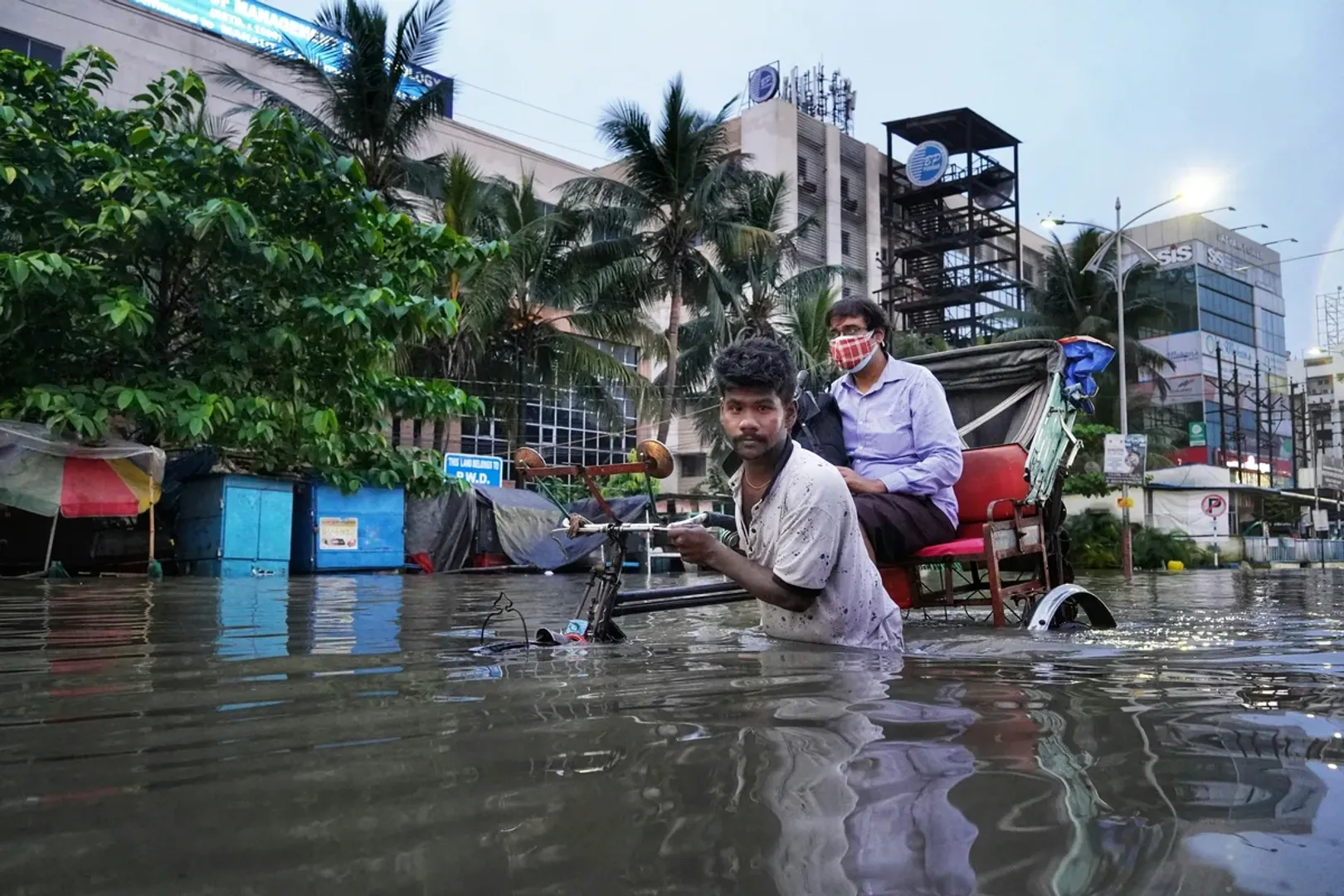 a-man-pulling-a-rickshaw-in-a-flooded-street