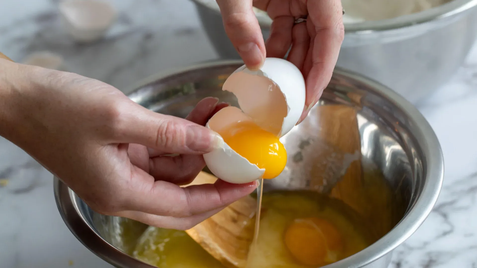 hands_cracking_egg_into_metal_bowl