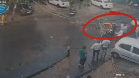 Delhi News: स्‍कूटी सवार महिला पर गिरा बिजली का खंभा, बाल- बाल बची, देखें Video