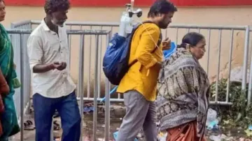 Man carries oxygen cylinder on shoulder