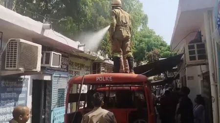 वकील के बस्ते के ऊपरी हिस्से में लगी आग बुझाता फायरकर्मी। 