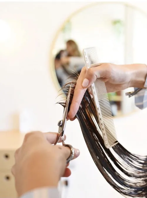 This may contain: a woman is cutting her hair with scissors