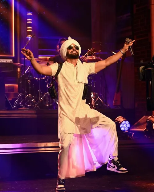 This may contain: a man is performing on stage with his hands in the air