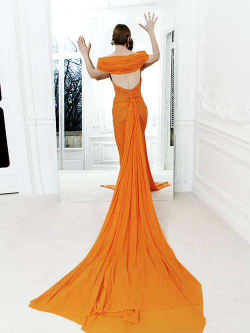 Woman in an orange gown standing in front of a mirror.