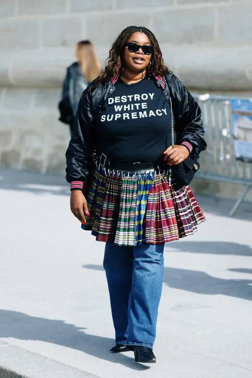 person wearing a statement tshirt and a skirt made of plaid fabric with denim jeans