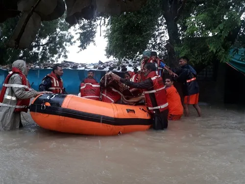 बारां जिले के किशनगंज क्षेत्र में बाढ़ से घिरे लोगों को बचाते SDRF टीम के जवान। - Dainik Bhaskar